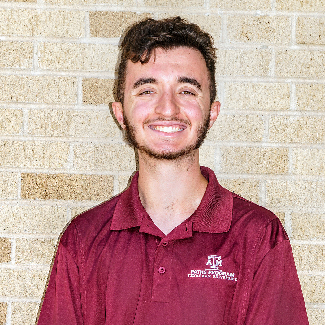 Jackson McGinnis, a young person with dark hari and facial hair wearing a red polo show.